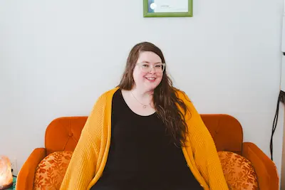 Kelli sitting on an orange couch.