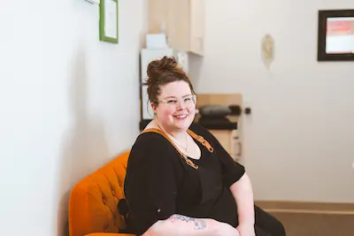 Kelli sitting on an orange couch.